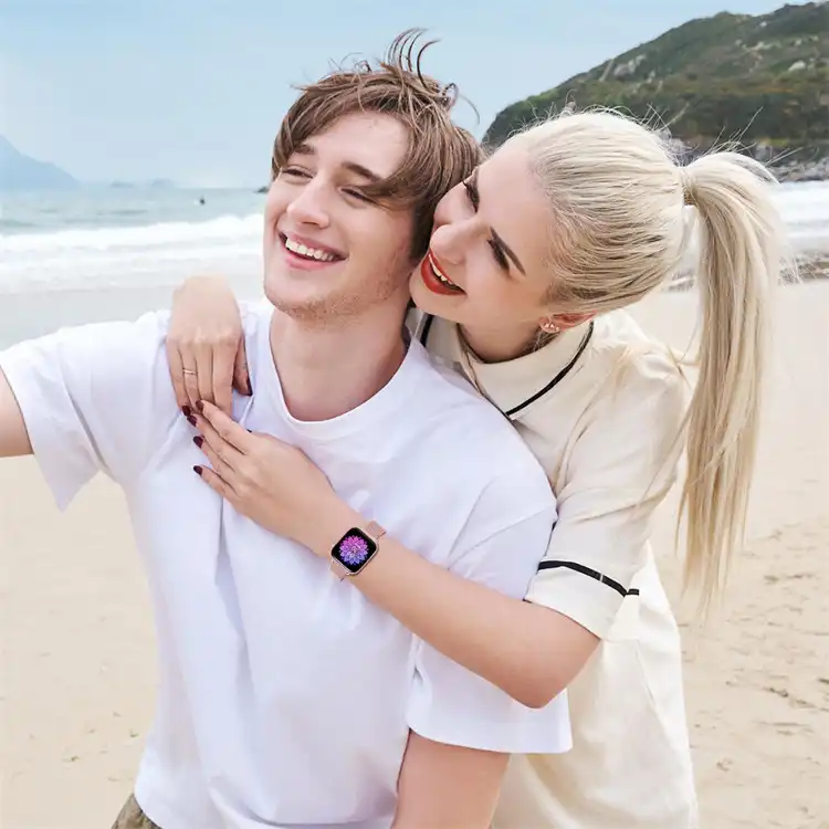Two models wearing rose gold milanese metal apple watch bands on a sunny beach.